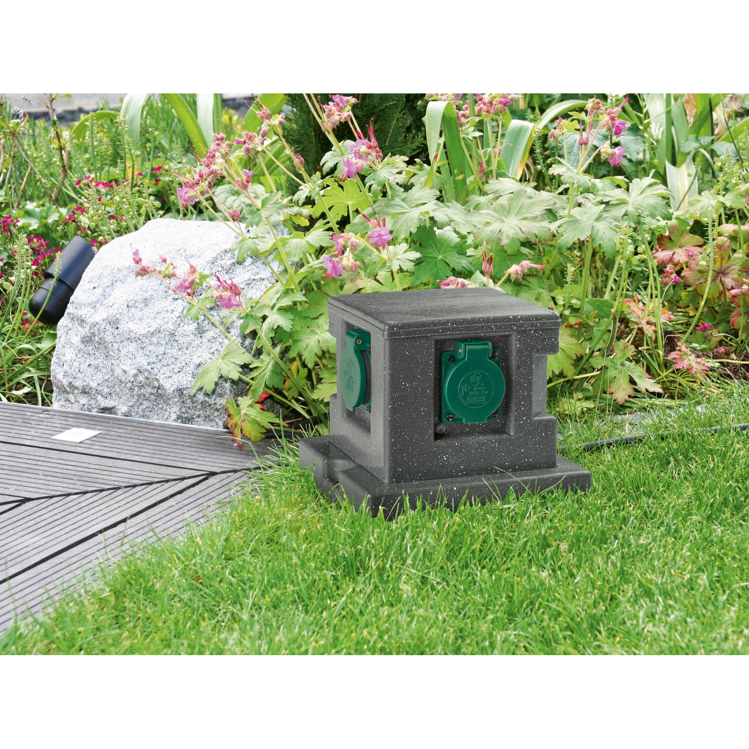 Gartensteckdose in Steinoptik mit 4 Steckdosen und grünen Schutzdeckeln im Garten.