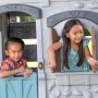 Kinder spielen im Step2 Adventures 2-Etagen Spielhaus mit Rutsche im Garten.