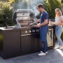 Buschbeck Outdoorküche Liverpool Schwarz mit Grill, Spüle und Kühlschrank im Garten.