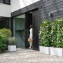 Weißer Elho Vivo Next Lang Blumentopf 59 cm mit Rollen vor modernem Haus.