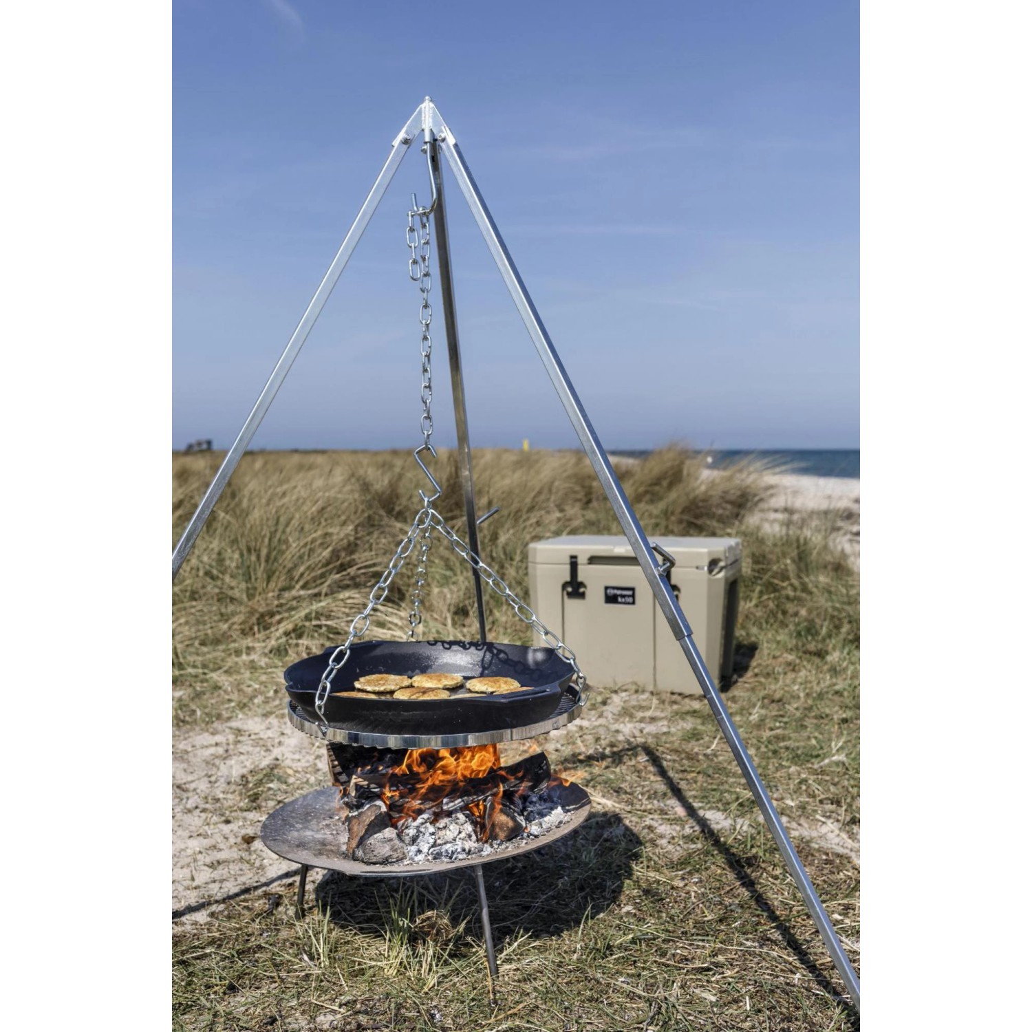 Petromax Feuerpfanne FP50H-T auf Dreibein über Feuerstelle. Gusseisenpfanne mit Speisen, Ø 50 cm.