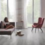 Heller Check One Click-Vinylboden Vogelsang Eiche im Wohnraum mit Sessel und Couch.