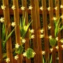Solar-Lichterkette mit 20 warmweißen Kirschblüten-LEDs an einem Holzzaun für stimmungsvolle Gartenbeleuchtung.