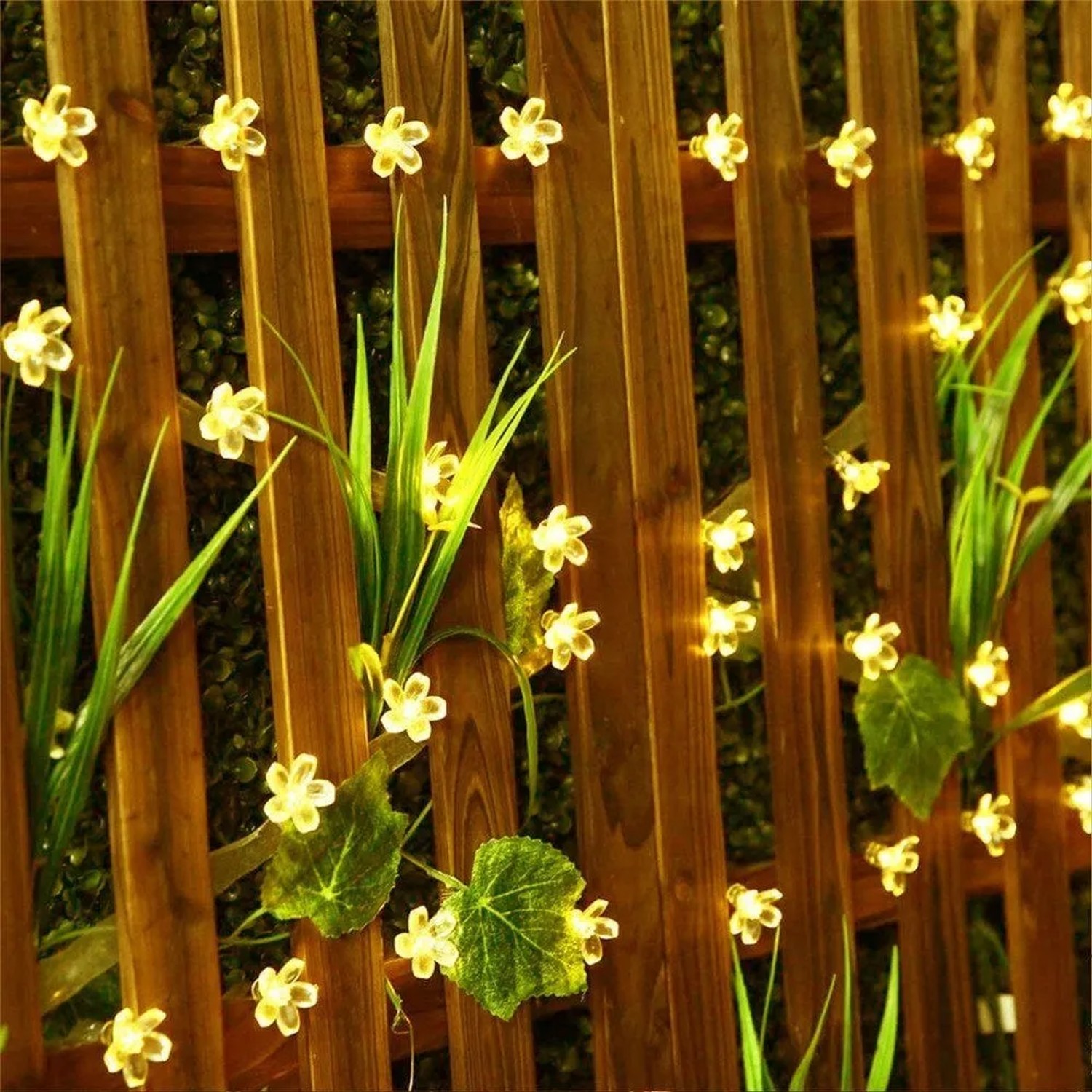 Solar-Lichterkette mit 20 warmweißen Kirschblüten-LEDs an einem Holzzaun für stimmungsvolle Gartenbeleuchtung.