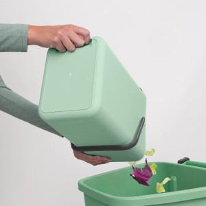 Grüner Brabantia Abfallbehälter Sort & Go (12 l) wird in einen größeren Mülleimer entleert.