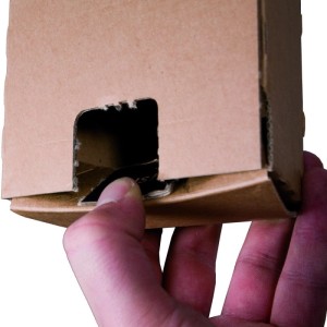 Hand sichert braune Trapez-Versandverpackung aus Wellpappe mit Haftklebeverschluss. Ideal für gerollte Produkte.