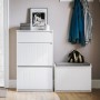 Weißer Schuhschrank mit 2 Klappen, 1 Schublade und Rillenfronten im Flur. Schmale Schuhkommode für platzsparende Aufbewahrung.
