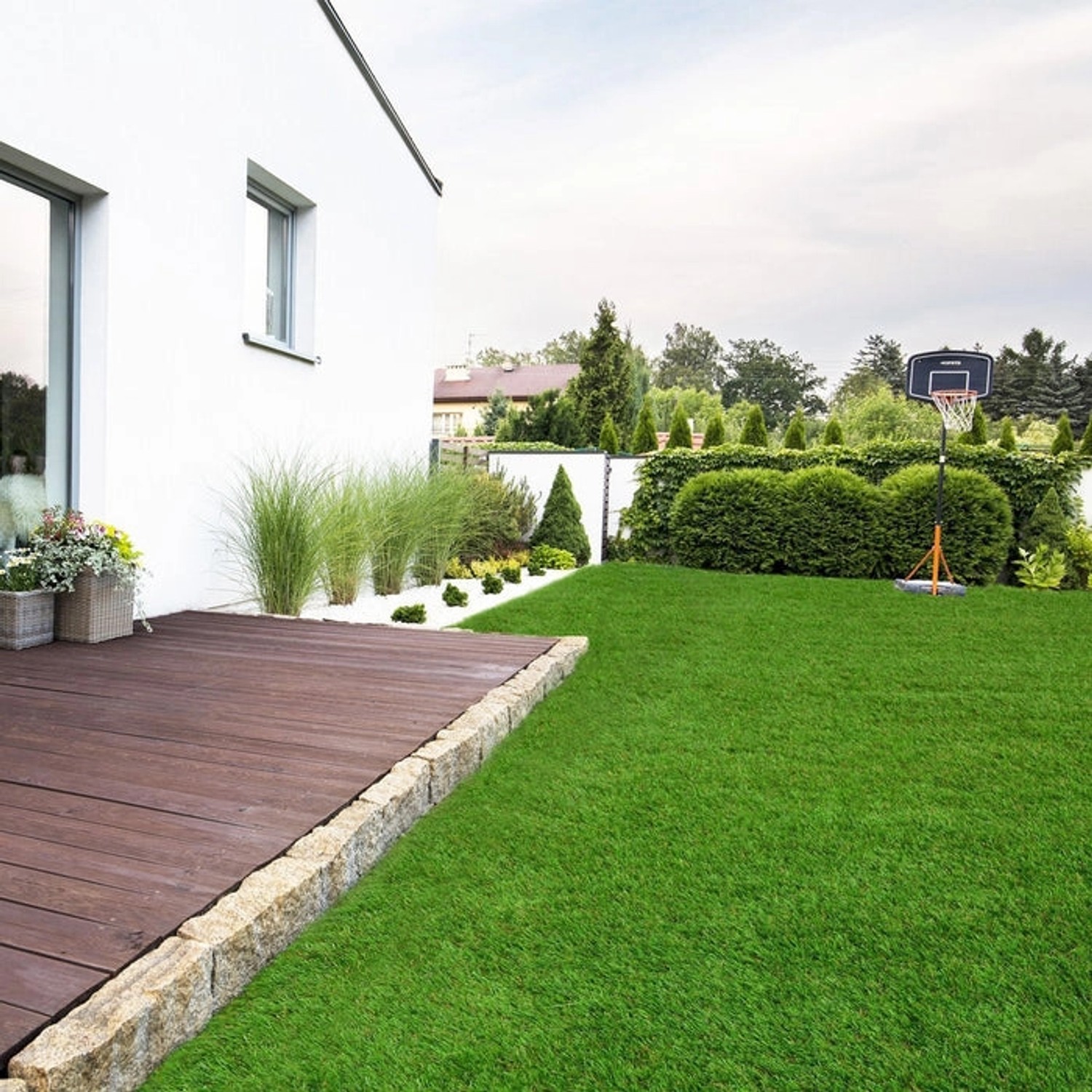 Sonniger Garten mit Karat Kunstrasen Lemon 50mm, ideal für entspannte Stunden im Freien.