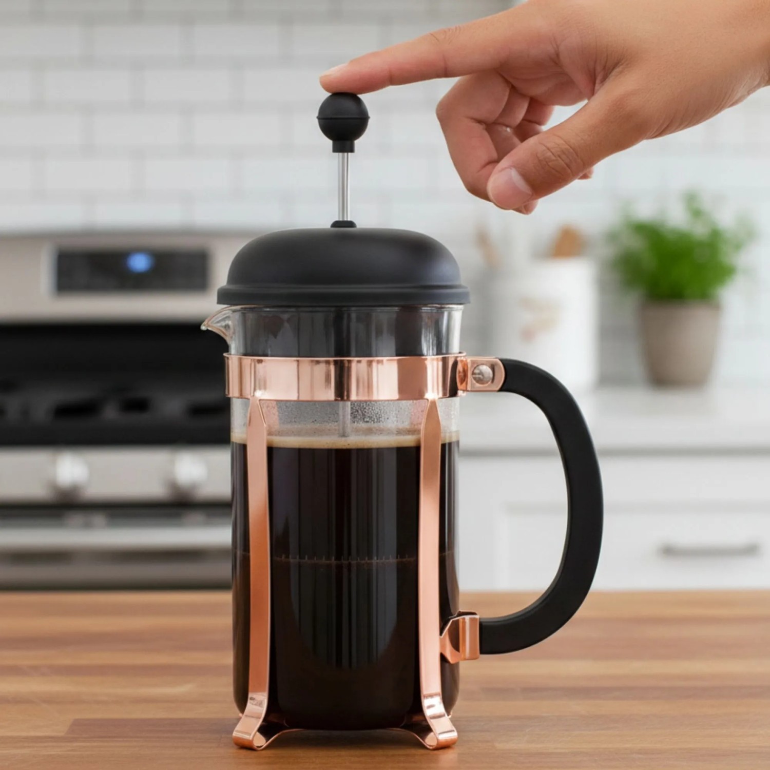 Kupferfarbener Bodum French Press Kaffeebereiter 1,0l mit Glasbehälter. Eine Hand drückt den Stempel.