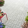 Verlegtes Rechteck-Pflaster Beton, weiß gewaschen, 20x10x6 cm, auf Terrasse mit Bepflanzung.
