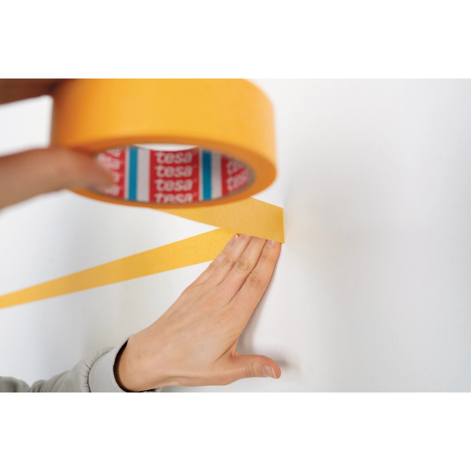Anwendung von tesa® Malerband Perfect+ zum Abkleben einer Wand für präzise Farbkanten.