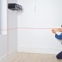 Bosch Quigo Kreuzlinienlaser mit MM 2 Universalklemme im Einsatz zum Ausrichten von Holzleisten.