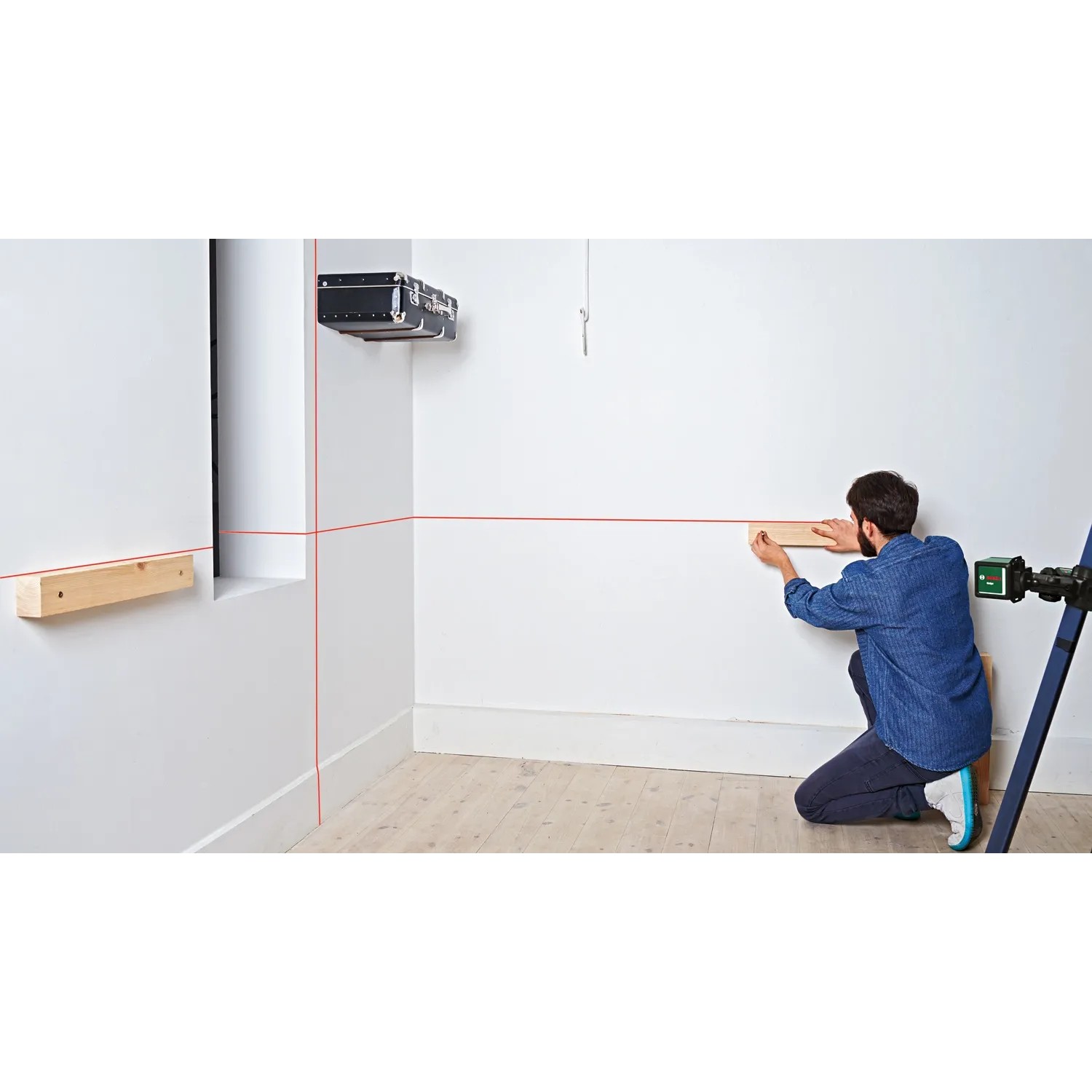 Bosch Quigo Kreuzlinienlaser mit MM 2 Universalklemme im Einsatz zum Ausrichten von Holzleisten.