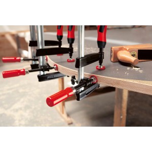 Bessey Kantenzwinge KT5-1CP beim Spannen einer Holzplatte. Spannwerkzeug mit rotem Griff.