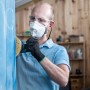 Mann schleift blaue Holzoberfläche mit Bosch Expert Schleifblatt C470 und Exzenterschleifer.