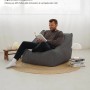 Mann liest entspannt im anthrazitfarbenen mokebo Cord Sitzsack Sessel mit Hocker.