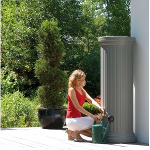 Garantia Regenwassertank 330 l in Steingrau mit Frau und Gießkanne im Garten.