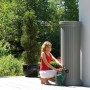 Garantia Regenwassertank 330 l in Steingrau mit Frau und Gießkanne im Garten.