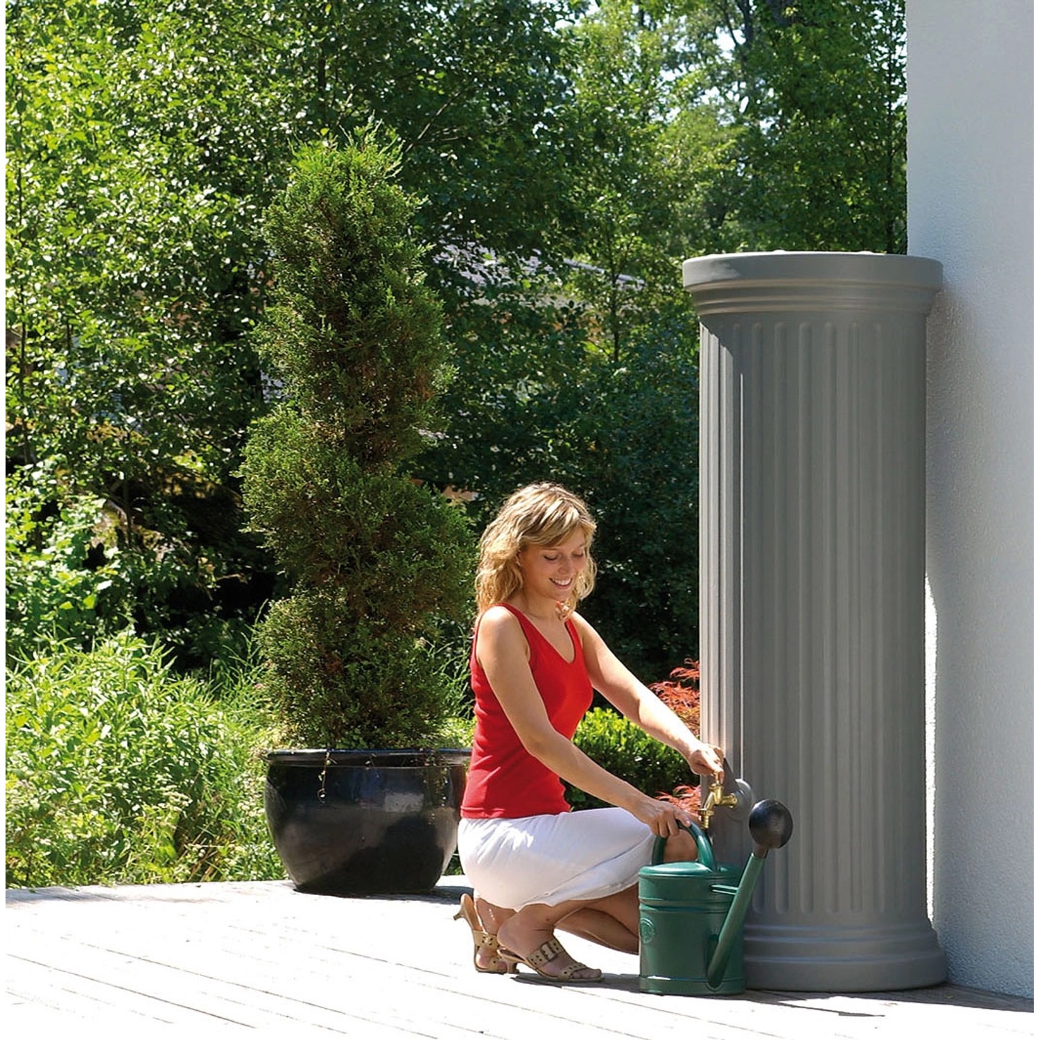Garantia Regenwassertank 330 l in Steingrau mit Frau und Gießkanne im Garten.