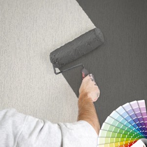 Mann streicht weiße Struktur Vliestapete mit Farbroller grau. Farbfächer im Bild.