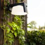 Lutec Solar-LED-Wandleuchte Moon, anthrazitfarben, an Holzwand mit Efeu.