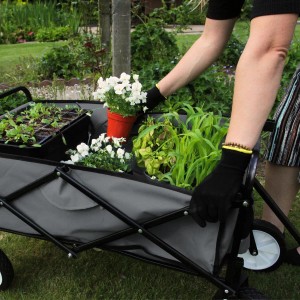 Grauer Monstershop Faltbarer Gartenwagen mit Pflanzen und Person im Garten.
