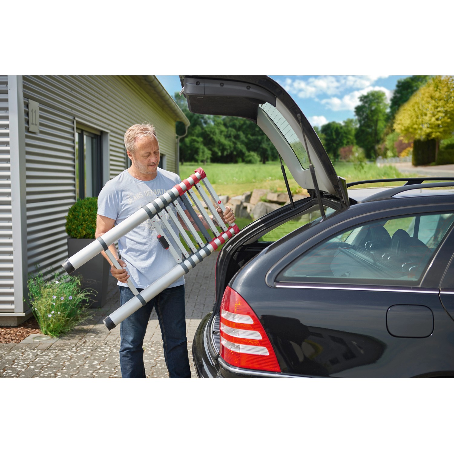 Mann verstaut Hailo FlexLine Teleskopleiter (9-stufig) im Kofferraum. Aluminium Leiter bis 150 kg.