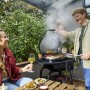 Schwarzer Char-Broil Elektrogrill Patio Bistro E2Coal beim Grillen mit Personen.