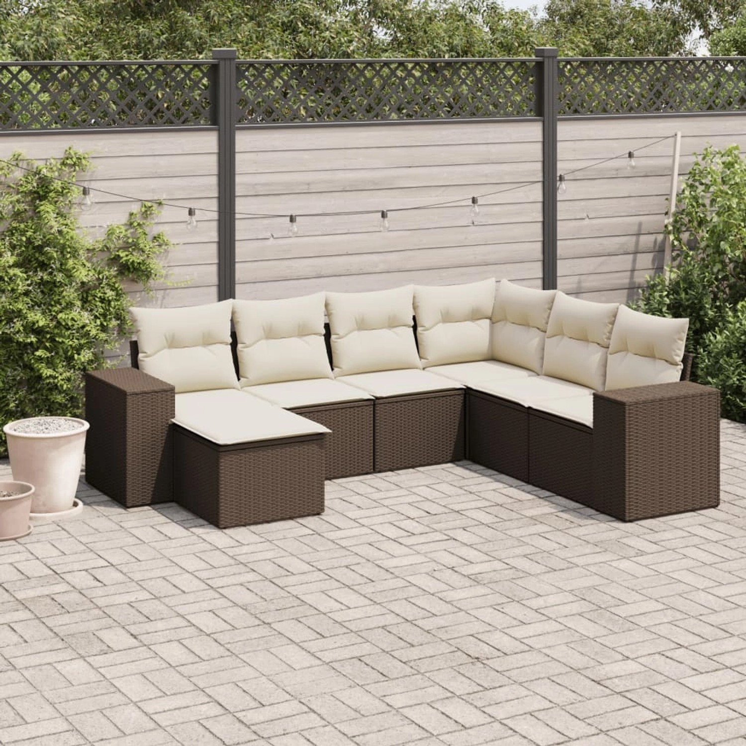 Braune 7-tlg. vidaXL Garten-Sofagarnitur aus Poly Rattan mit cremefarbenen Kissen auf einer Terrasse.