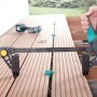 Wolfcraft Terrassenbau Set im Einsatz: Montagezwinge fixiert Terrassendielen, Abstandshalter sichtbar.