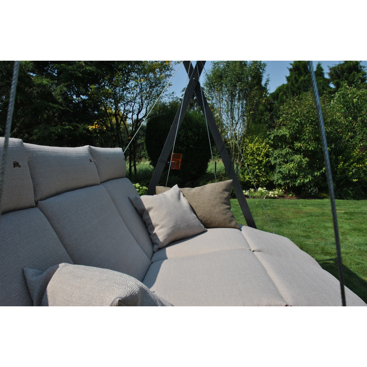 Hollywoodschaukel Relax Smart Sand mit Liegefläche, Kissen und Stahlrohrgestell im Garten.