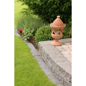 Anthrazit Mähkante klein (24x12x4,5 cm) als Rasenkante im Garten, neben einer Steinmauer.