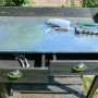 Schwarzer Pflanztisch aus Holz mit verzinkter Arbeitsfläche, zwei Schubladen und Ablage für Gartenzubehör.