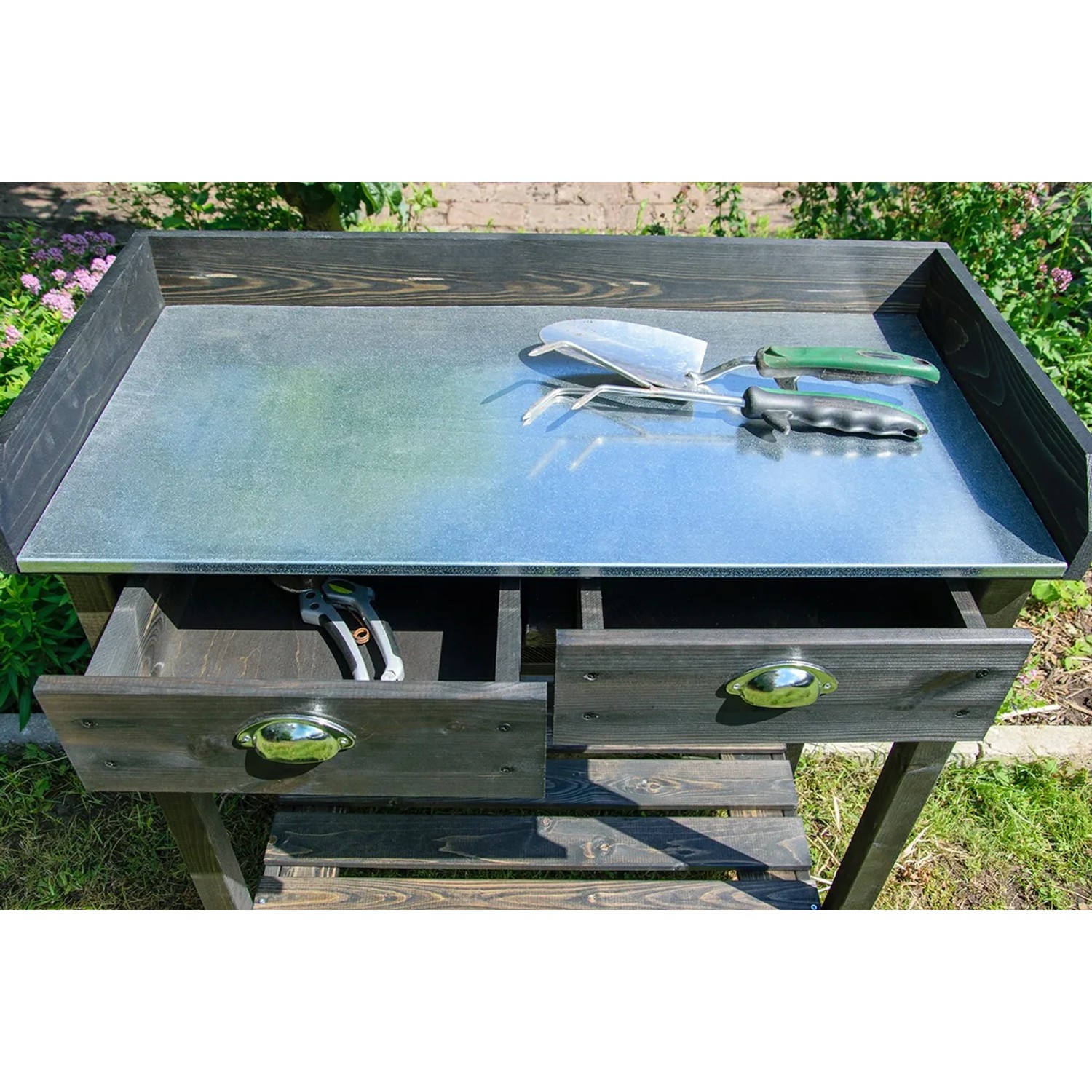 Schwarzer Pflanztisch aus Holz mit verzinkter Arbeitsfläche, zwei Schubladen und Ablage für Gartenzubehör.