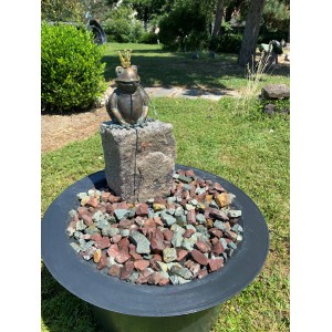 Gartenbrunnen-Set mit Bronze Froschkönig auf Granitstein in einem Becken mit Ziersteinen.