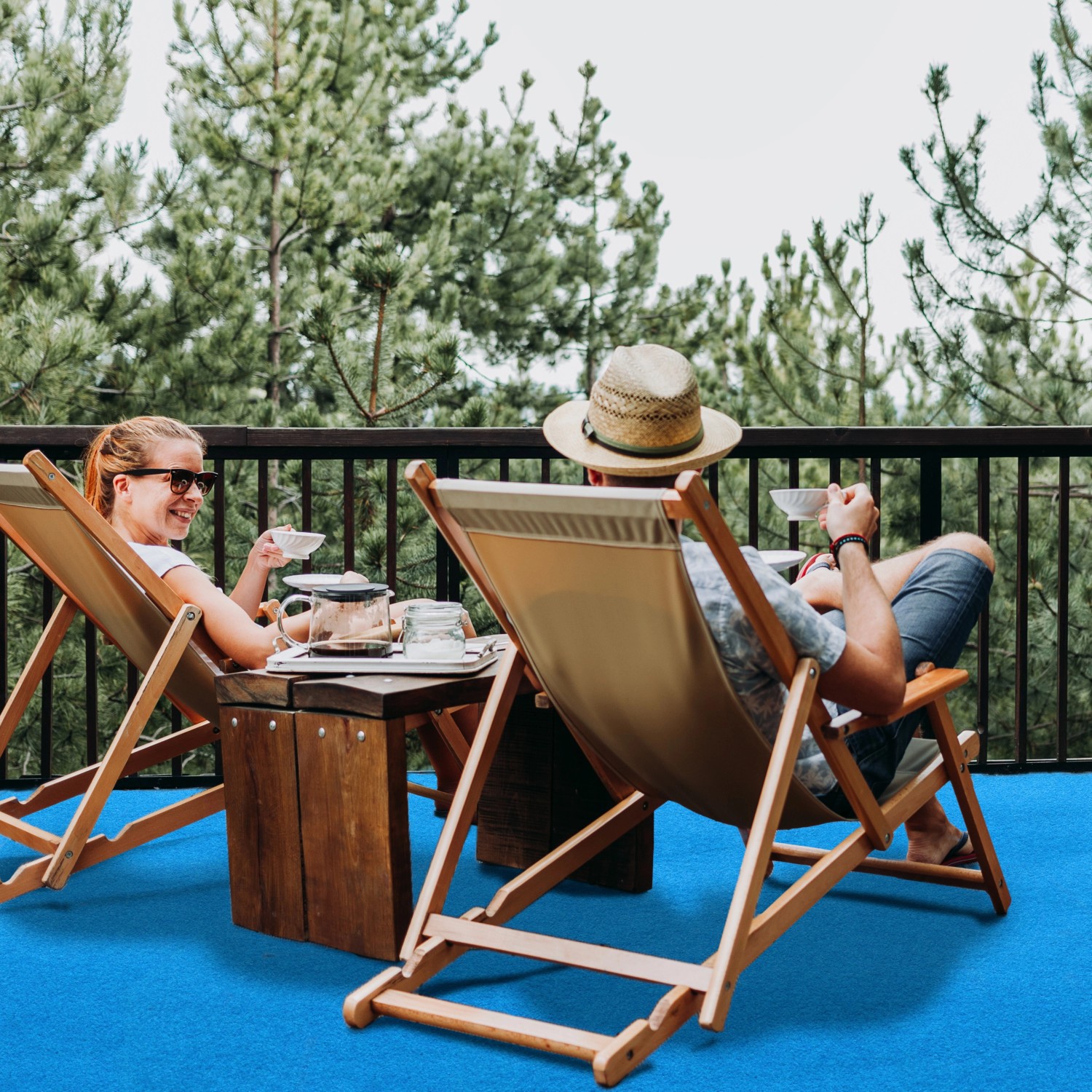 Blauer Primaflor Rasenteppich Park auf Terrasse mit entspannten Personen in Liegestühlen.
