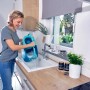 Frau leert blauen Leifheit Clean Twist Disc Mop Eimer in ein Waschbecken. Reinigungsgerät mit Schleuder.