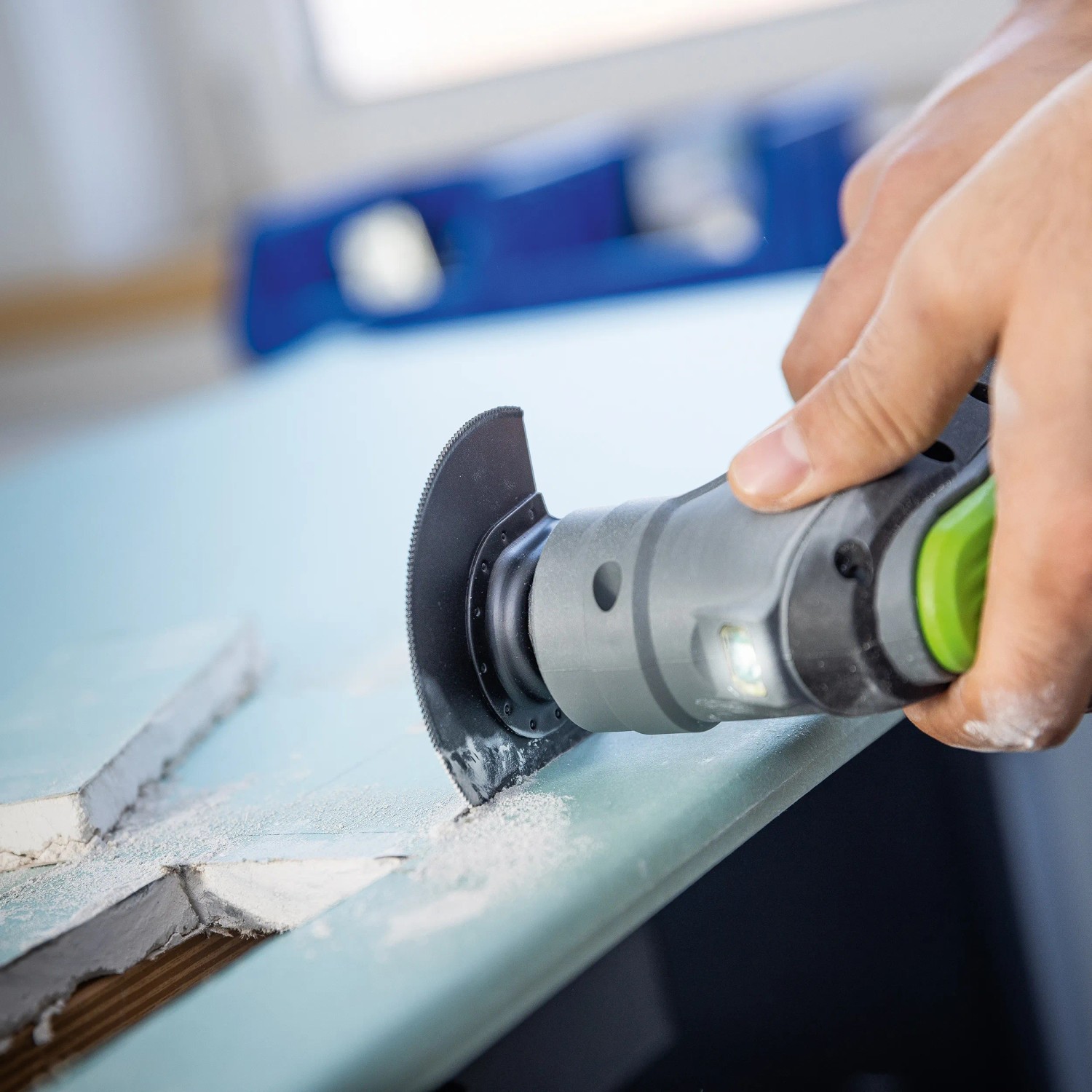 LUX Akku-Multi-Tool A-MFW-20 Solo beim Sägen. Das Multitool ist grau und schwarz mit grünem Akzent.