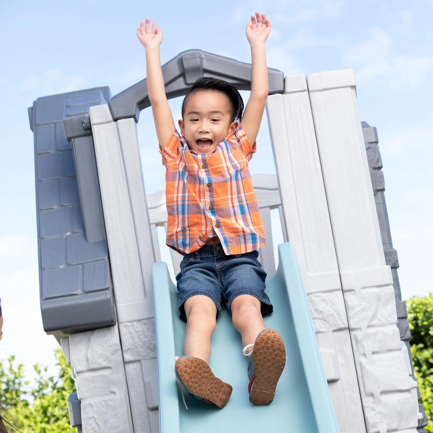 Kind rutscht auf der Rutsche des Step2 Spielhaus Adventures mit 2 Etagen.