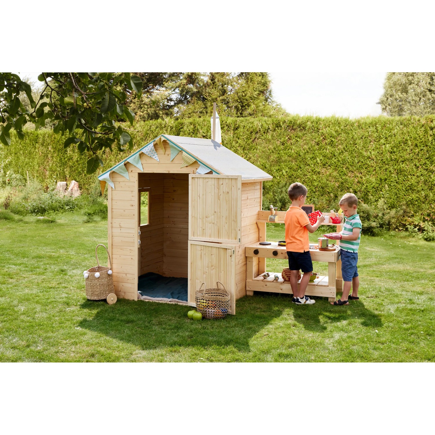 Soulet Kinderspielhaus Jasmine aus Holz mit Küche und zwei spielenden Kindern im Garten.