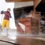 Kärcher eco!Booster Strahlrohr im Einsatz: Frau reinigt Holz mit Hochdruckreiniger.