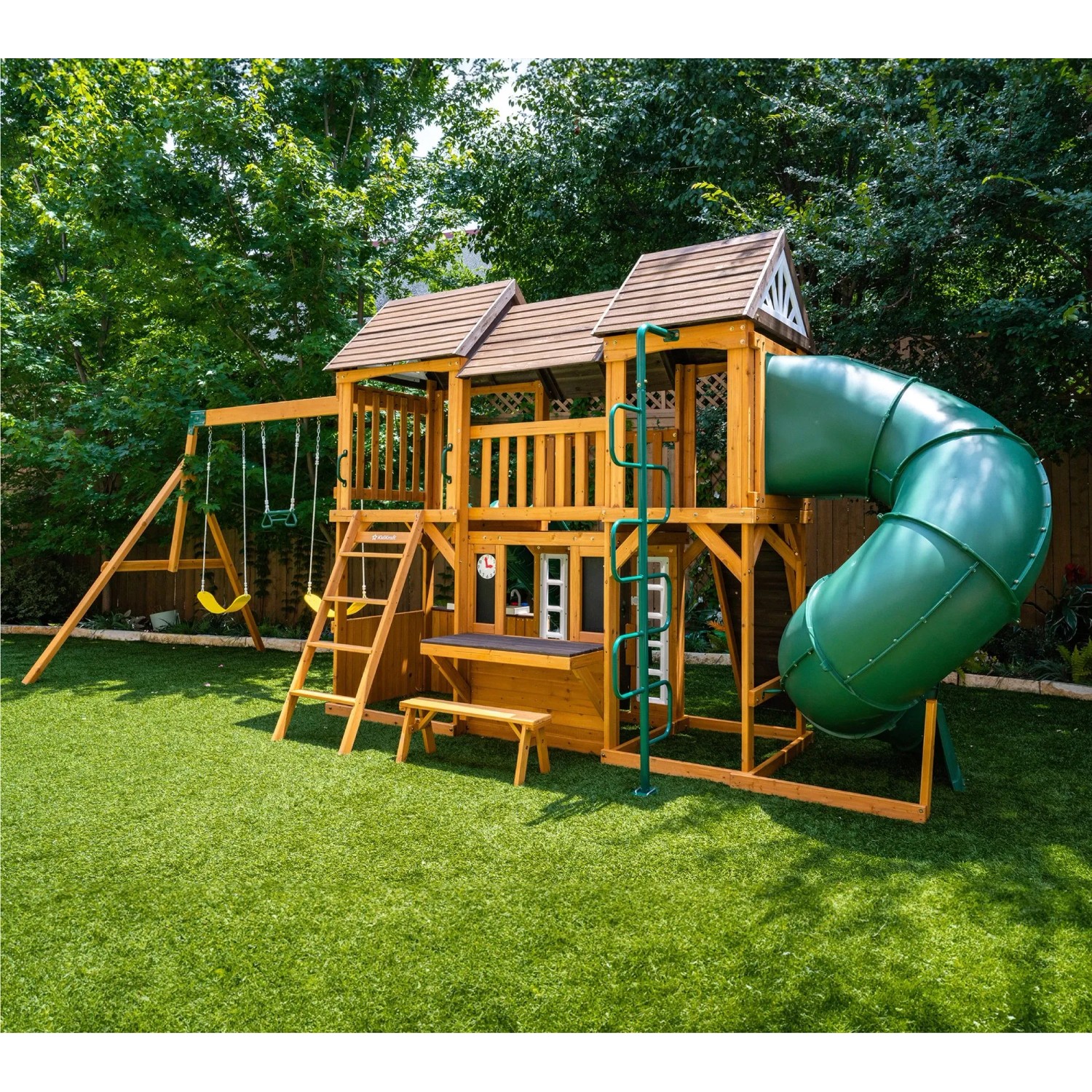 Zwerkules Bolzo Spielturm aus Holz mit grüner Tunnelrutsche, Doppelschaukel und Kletterwand im Garten.