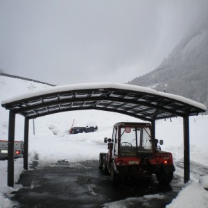 Mattbrauner Ximax Carport Portoforte-60 M mit Traktor im Winter.