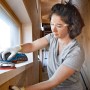 Frau schleift Fensterrahmen mit Bosch Professional Akku-Exzenterschleifer GEX 18V-125.