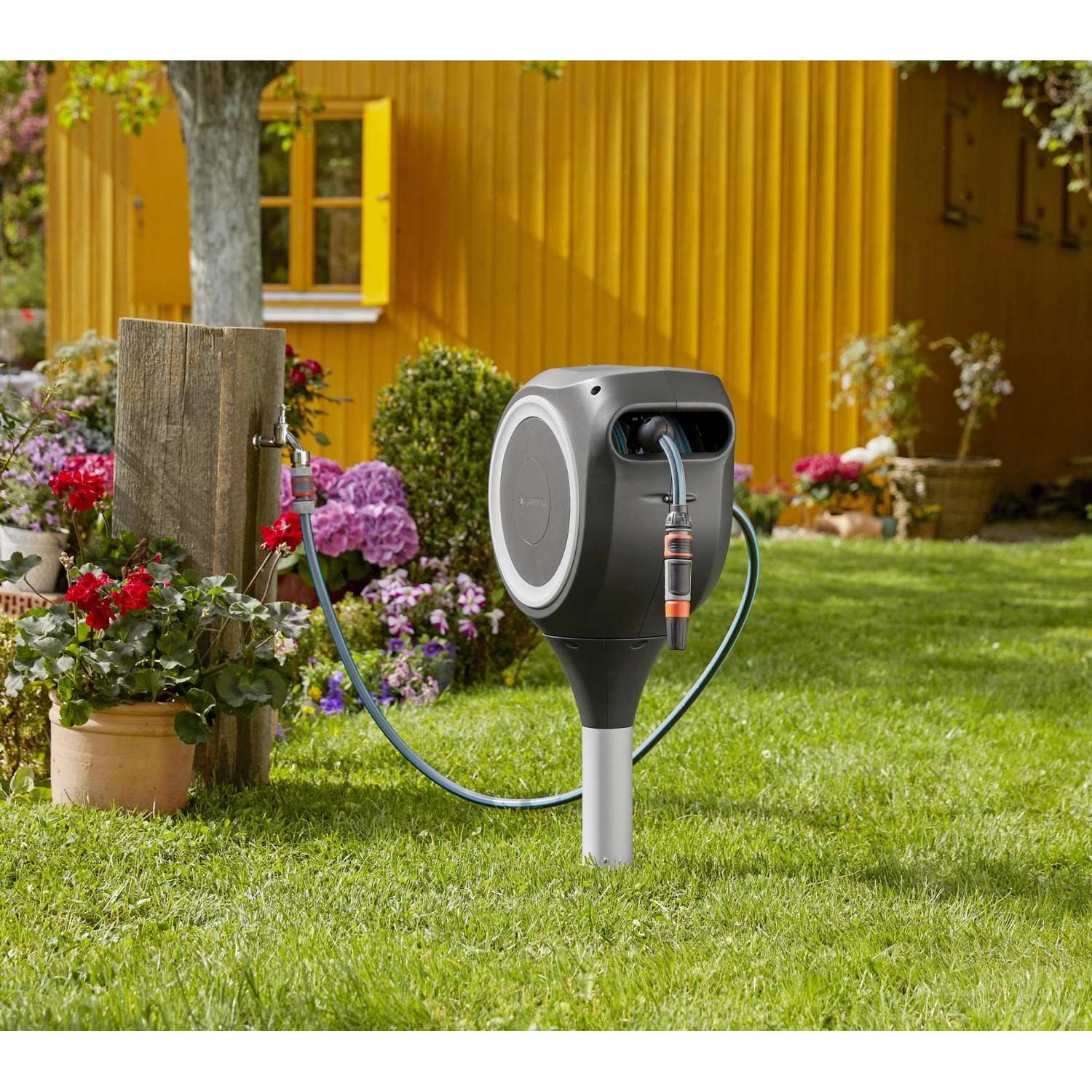 Gardena RollUp S 15 m Gartenschlauchbox mit Schlauch und Spritze im Garten.