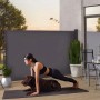 Juskys Seitenmarkise Dubai, 500x180cm, Dunkelgrau. Frau macht Yoga mit Hund vor der Markise auf Terrasse.