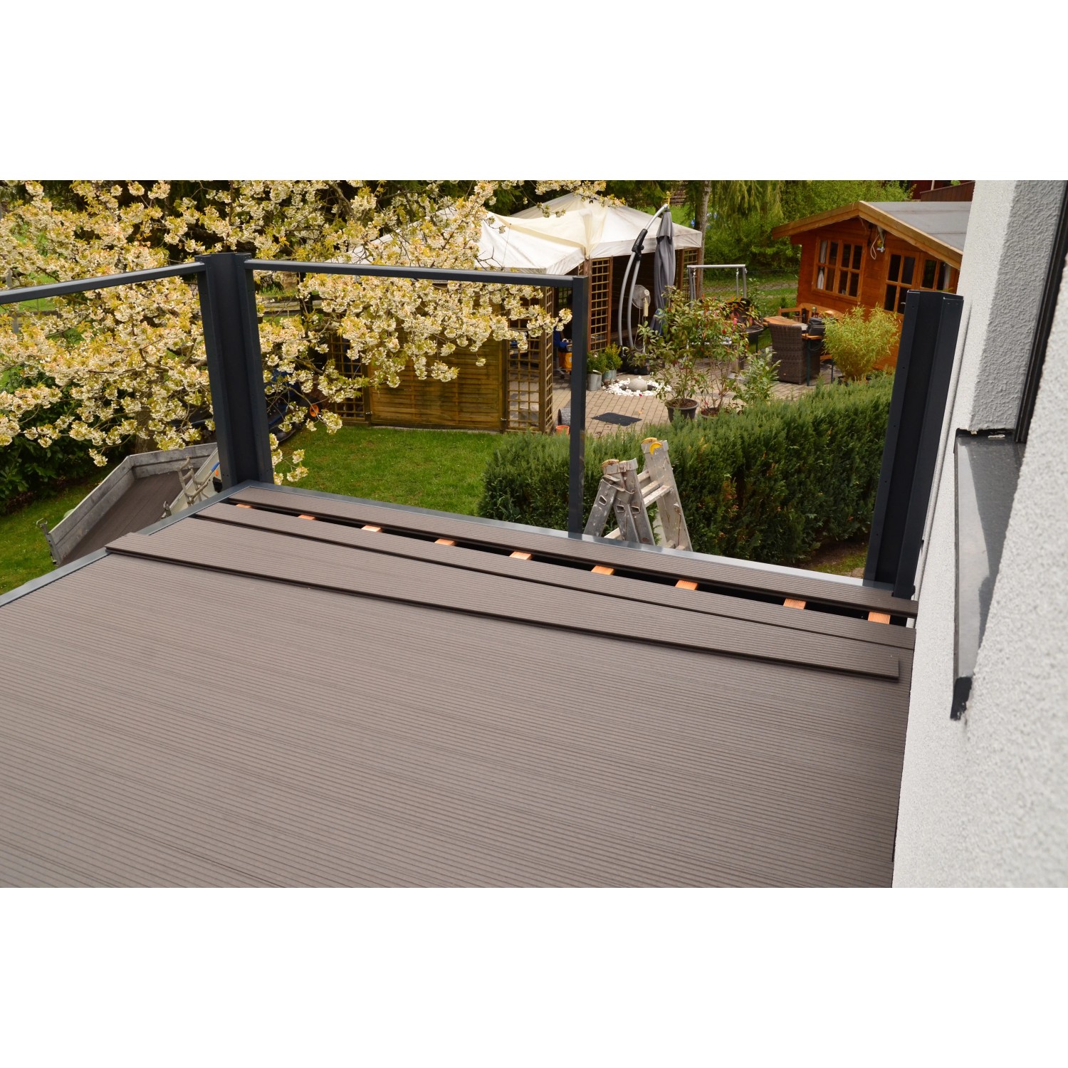 Designbalkon mit BPC-Boden in Anthrazit und Lamellengeländer, montiert im Garten.