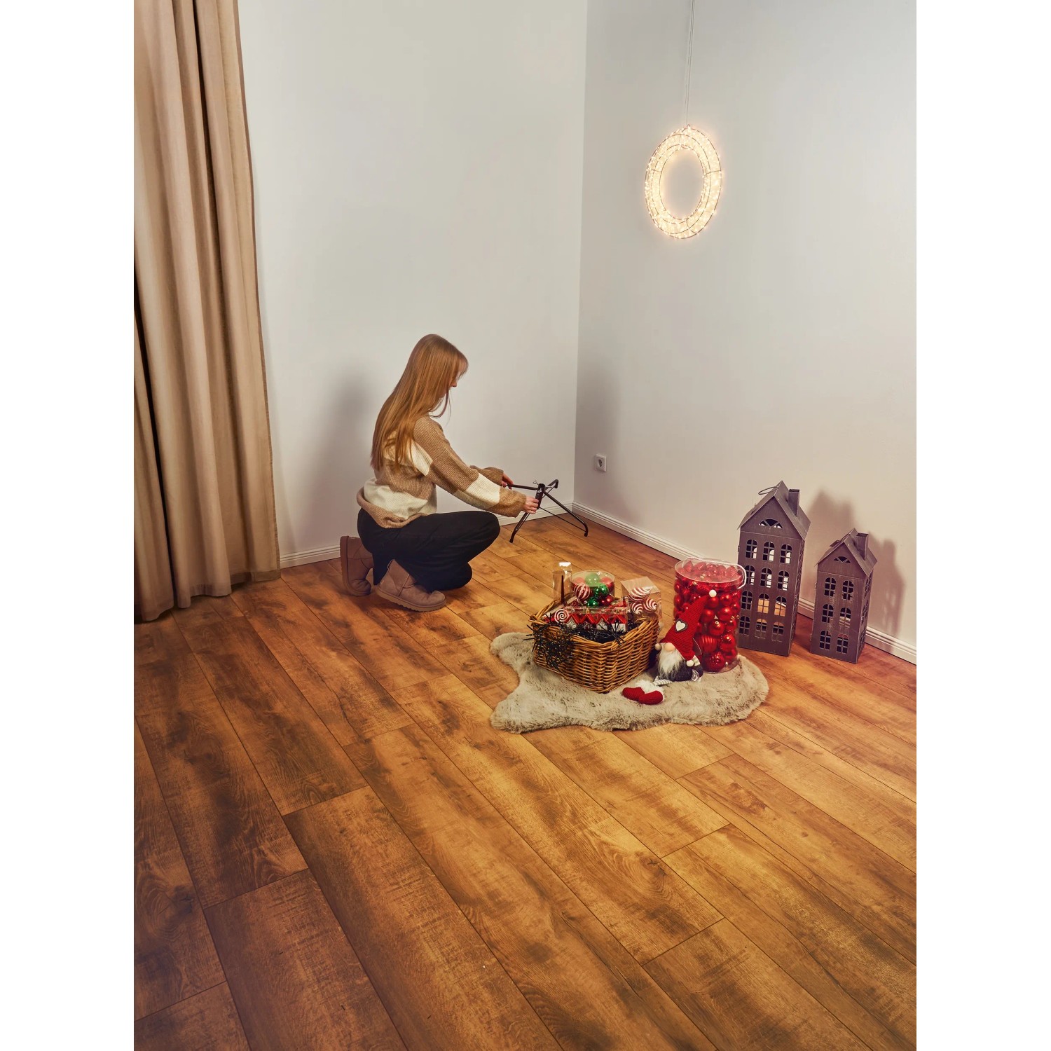Frau baut künstlichen Weihnachtsbaum Nagano (150cm) auf. Deko-Elemente im Raum.