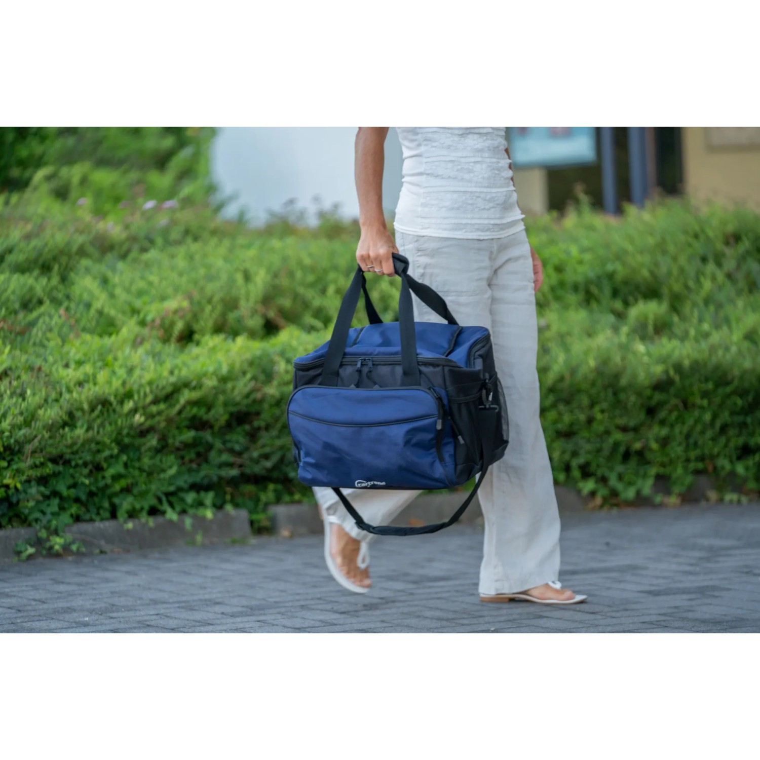 Blaue Cartrend Kühltasche (30 l) mit Tragegurt, getragen von einer Person im Freien.