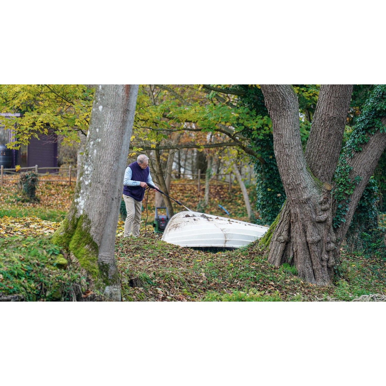 Mann reinigt Boot mit Bosch Akku-Hochdruckreiniger UniversalAquatak 36V-100 im Garten.